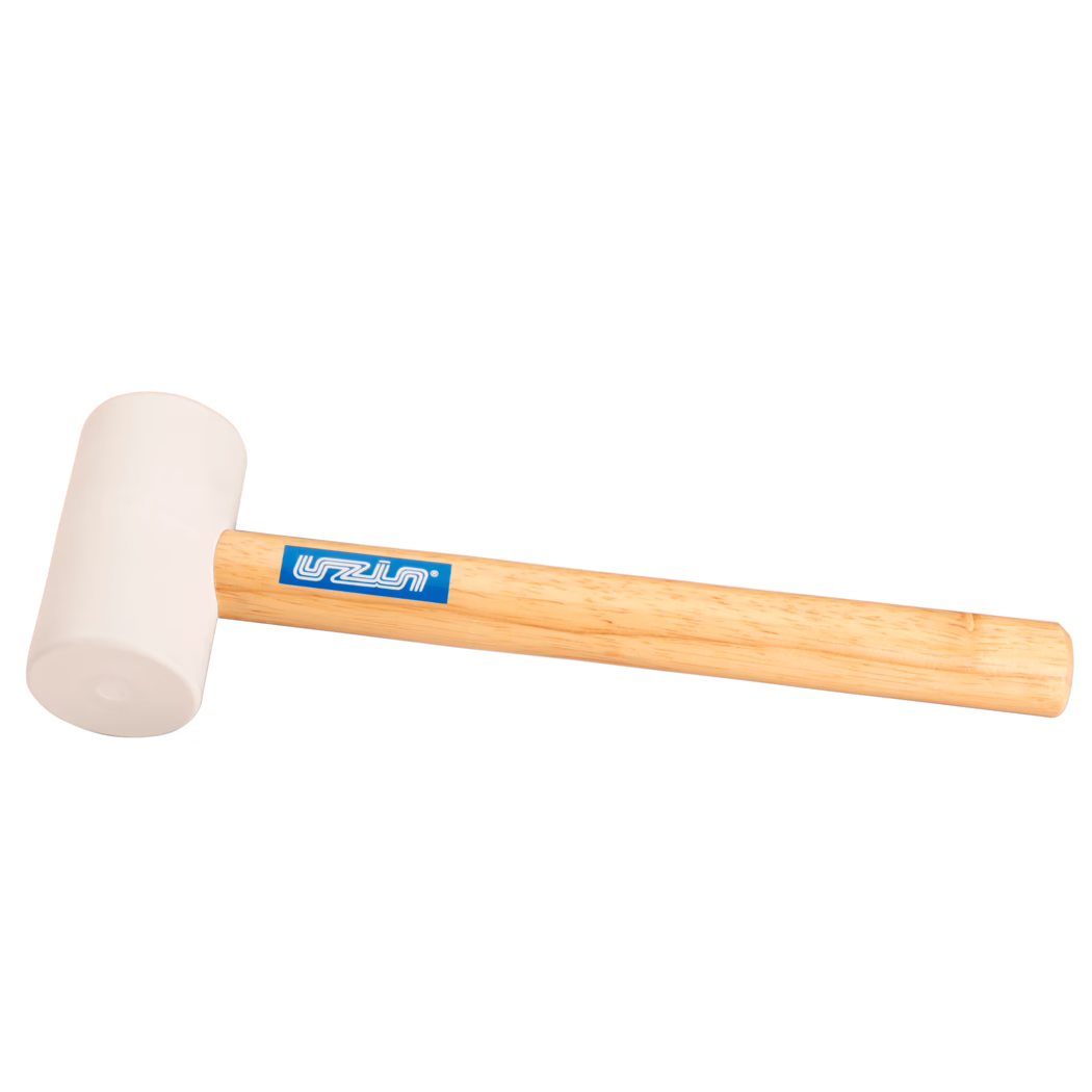 UZIN_Dummy_rubber hammer-UZIN_2014-11 Close-up productfoto van een rubberen hamer: een licht beige rubberen kop bevestigd aan een glad, licht houten handvat met een blauw rechthoekig merklabel; de hamer ligt diagonaal op een schone witte achtergrond, zacht verlicht zodat de rubberstructuur en houtnerf zichtbaar zijn; geschikt voor zachte klopwerkzaamheden bij houtbewerking, montage of tegelzetten.